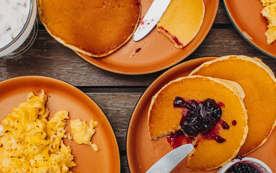 Mesa de desayuno con pancakes y huevos como referencia visual